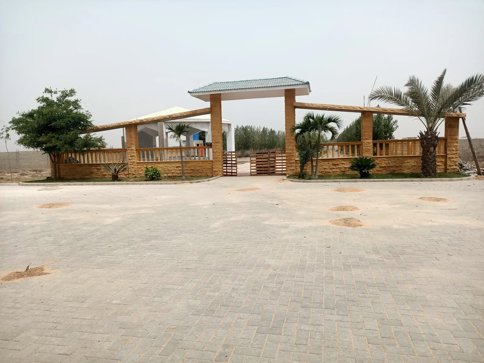The landscaped pavilion entrance with palms and a paved forecourt at Jannat City